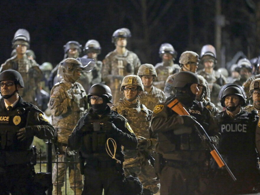 Police and Missouri National Guardsmen stand guard as protesters gather in front of Ferguson Police Department on Friday. Authorities made 15 arrests amid largely peaceful protests.