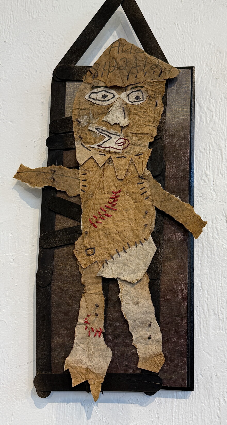 Ragged cardboard figure with staples and nails