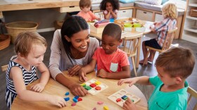 Teacher And Pupils Using Wooden Shapes In Montessori School