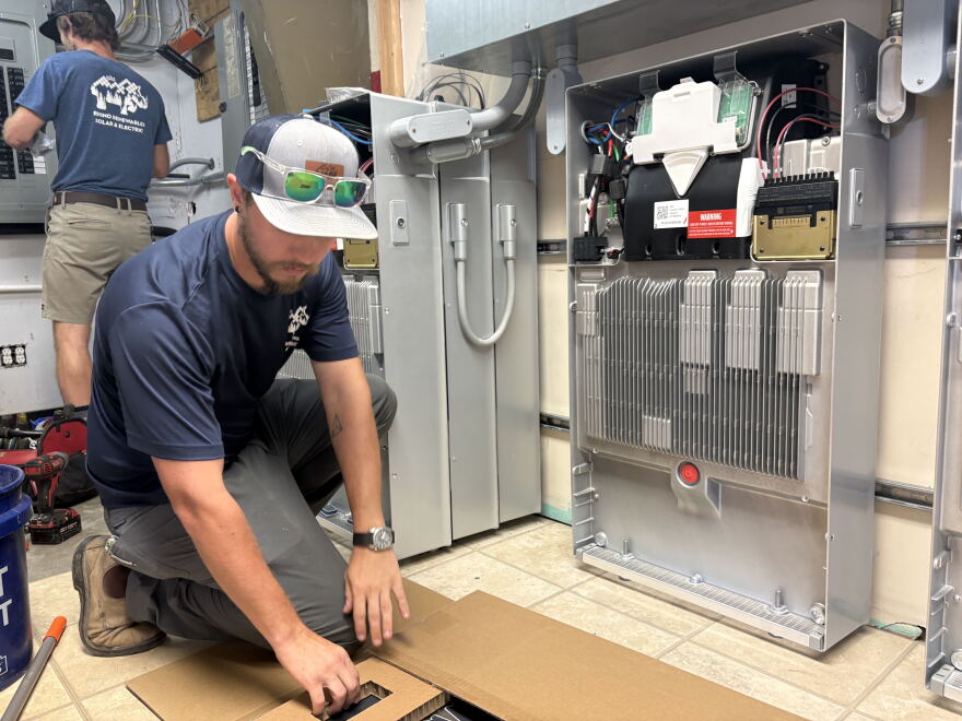 Ryan Callahan, an electrician with Rhino Renewables, puts the final touches on the first DEQ-funded solar microgrid project.