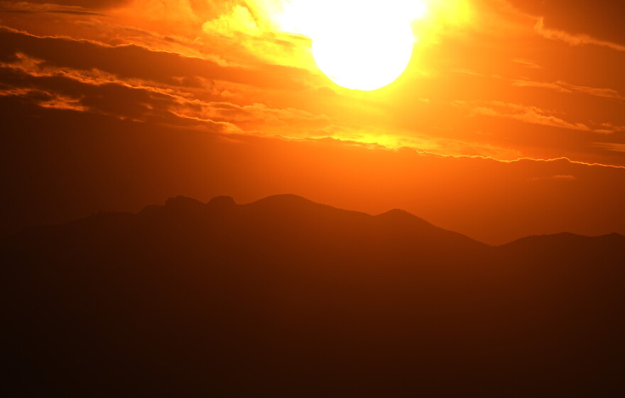 The setting sun illuminates the clouds over the Rocky Mountains.
