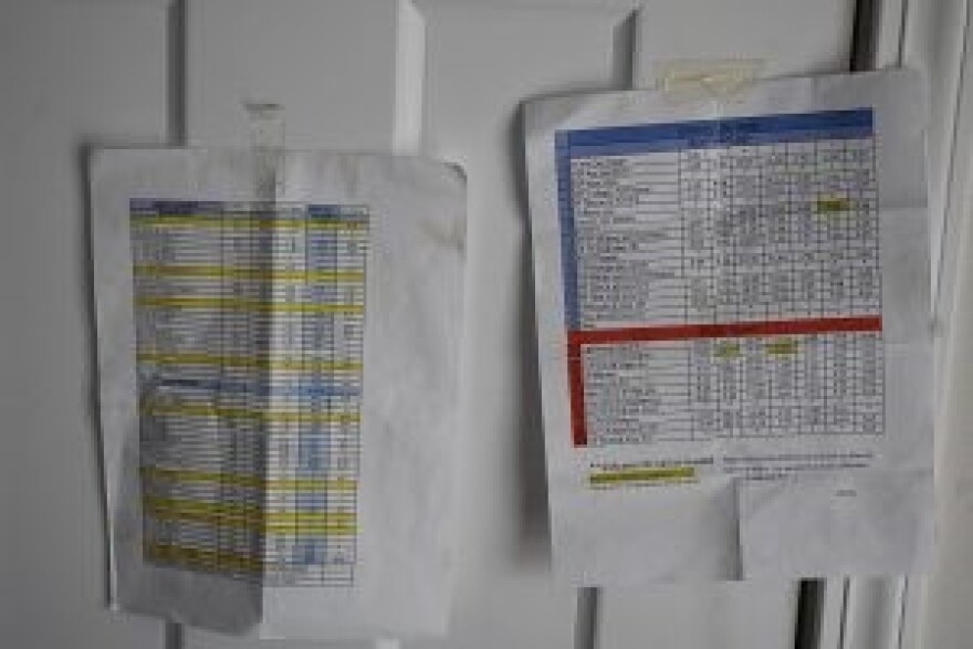 Pieces of paper with bus schedules attached taped to a wall