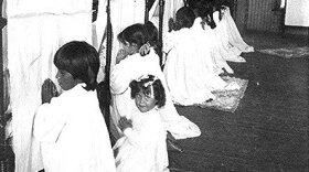 Young girls praying beside their beds at Phoenix Indian School