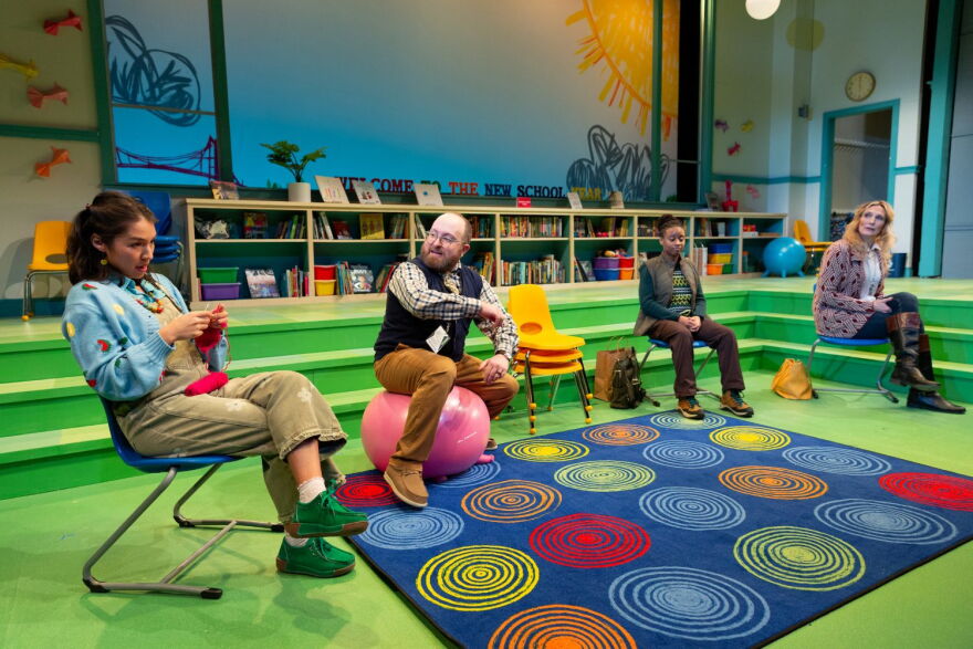 Four performers on a stage set designed to look like an elementary school library.