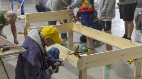 A man is kneeled down building a bed frame.