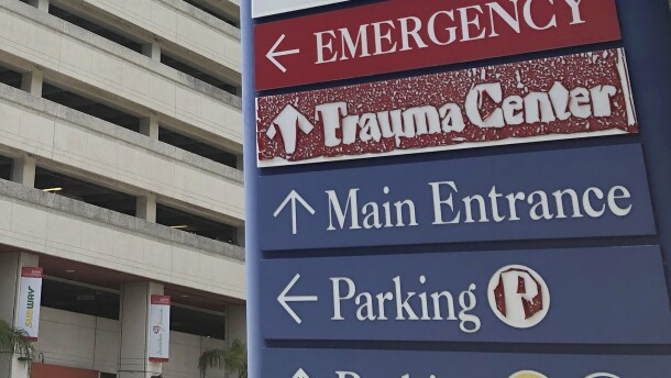 A sign that points to the emergency room, trauma center, main entrance, and parking at a Miami hospital. 