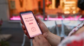 A woman holds up a phone screen with a 'Buy Now, Pay Later' advertisement up. 