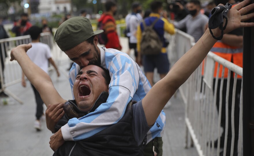 Mourners embrace as they wait to see Diego Maradona lying in state outside the presidential palace in Buenos Aires on Thursday.