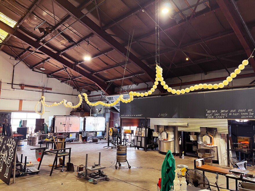 Multiple glass blowing stations inside an old industrial building.