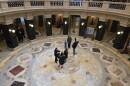 Tourists mill in center of Wisconsin State Capitol and point upwards at the dome.