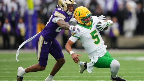 Washington safety Vincent Holmes (27) tackles Oregon quarterback Dante Moore during the first half of an NCAA college football game, Saturday, Nov. 29, 2025, in Seattle. (AP Photo/Lindsey Wasson)