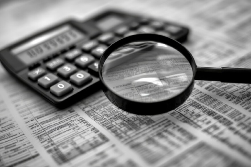 Stock photo depicting a magnifying glass, a calculator and financial documents.