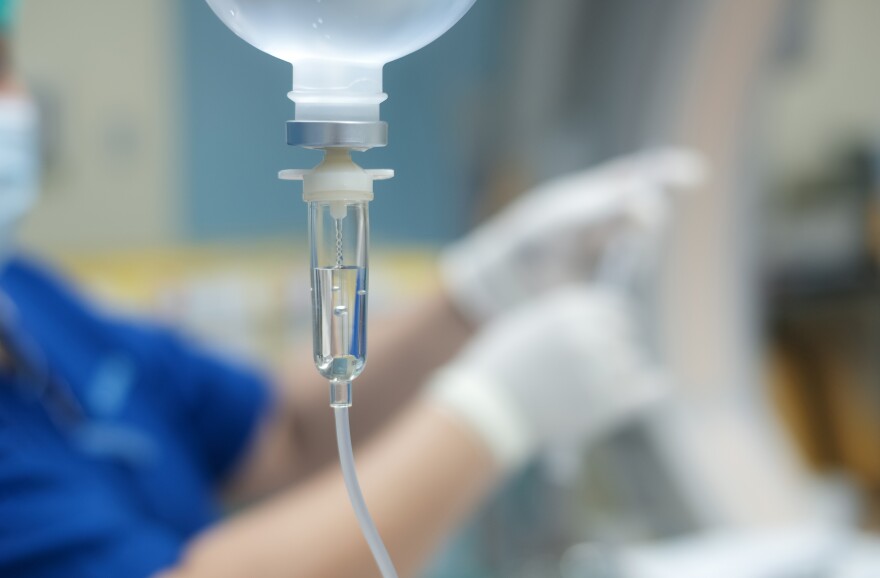A healthcare worker administers IV fluid. 