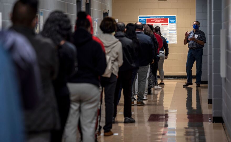 A poll worker talks to a line of voters on Election Day 2020 in Austin, Texas.