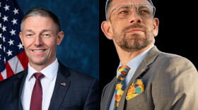 Two photos of white men sit side by side. On the left is a middle-aged man with greying short hair. He wears a navy blue suit jacket with an American Flag pinned to his left collar. Underneath the jacket is a maroon tie and a white button down shirt. The American Flag is to the left of him in the background and on the right is a washed looking dark blue background. The right photo is a sticker of a man with short brown hair and facial hair. He wears a khaki suit jacket with a colorful handkerchief in his breast pocket. It matches his tie with yellow, orange, turquoise, some red and blue geometric shapes. Underneath he wears a light blue button down shirt.