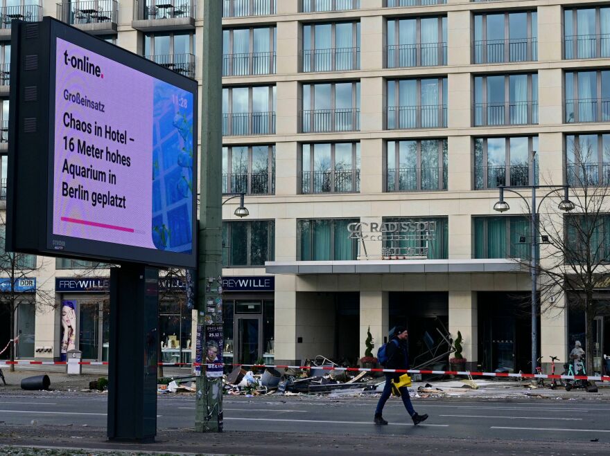 A screen displays the news "Major operation - Chaos in hotel - 16-meter high aquarium in Berlin exploded" in front of the Radisson Blu hotel, where a huge aquarium located in the hotel's lobby burst on Friday.