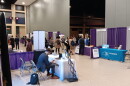 Attendees of the New York State Innovation Summit mingle in the section within the Buffalo Convention Center where booths were hosted by businesses and the state agencies that can help them with resources. Beyond the walls in the darkened section, a panel discussion was in progress.