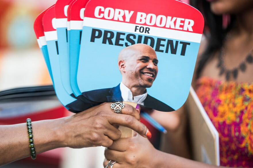 Supporters of Sen. Cory Booker share fans with the candidate's face. The 2020 presidential field, which includes at least three black candidates, is the most racially progressive ever.