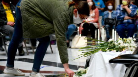 A person places a flower on a temporary memorial to commemorate Hoosiers who died as a result of a COVID-19 infection.