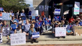 A group of students, many holding protest signs, rally at New College of Florida
