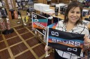 Lorena Ortega, the sales and marketing manager at Dixie Flag & Banner Company, holds up one of their best sellers—a Spurs car flag