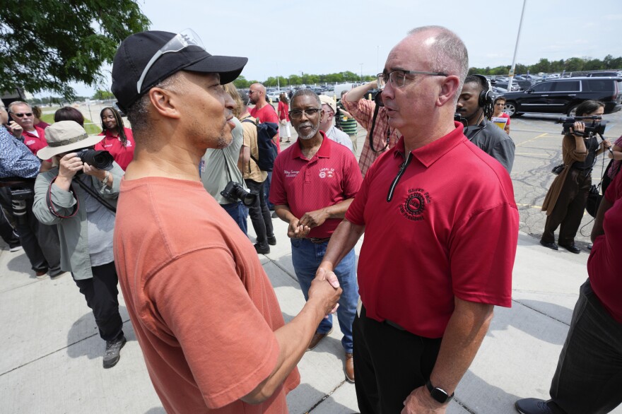 Autoworker Kevin Winston, left, talks with United Auto Workers president Shawn Fain outside the General Motors Factory Zero plant in Hamtramck, Mich., on July 12.