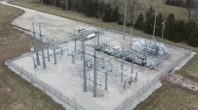 An aerial view of an electric substation. There is a square lot with steel poles and electrical boxes and wires connecting them.