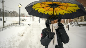 UConn student Michela Brown, a biology major and animal science minor, braces herself against the snow under the protection of a flower umbrella in Storrs on February 28, 2023. Despite classes being cancelled, Brown’s research project required her to walk across campus to the sheep pens to provide the animals their breakfast.