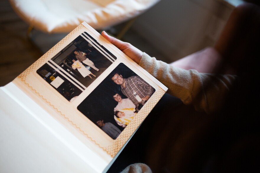 A woman holds an album where she's photographed with her family as a baby.
