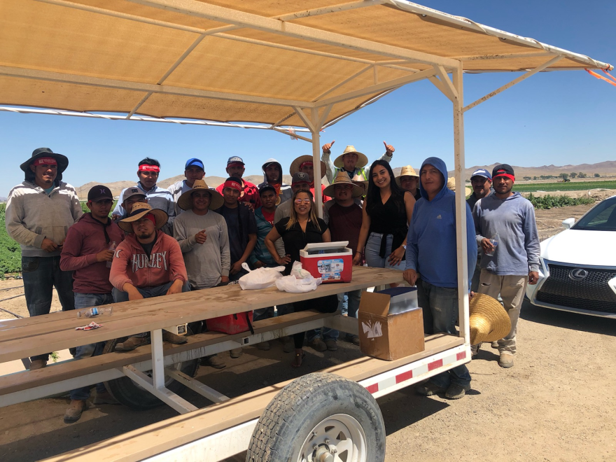 Over a dozen farmworkers gathered under a shade structure along with two employees of the Nevada Human Development Corporation.