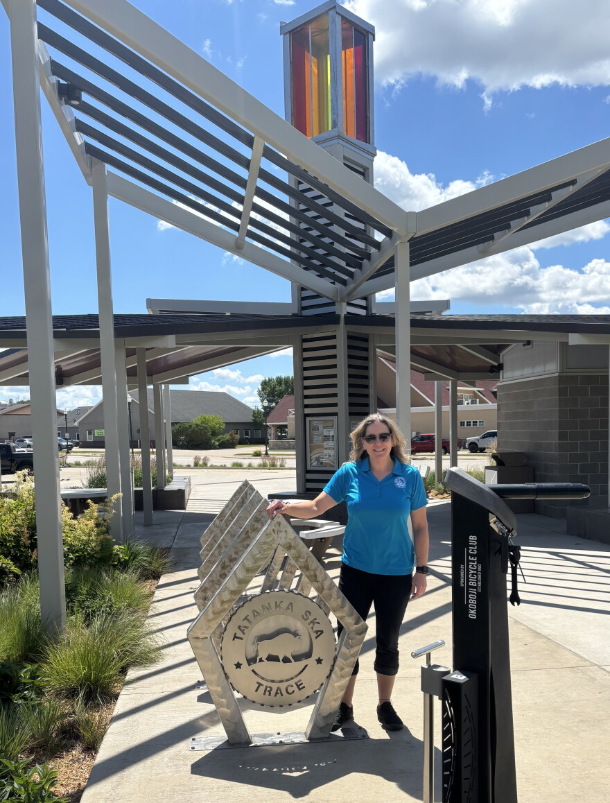 Erin Reed, executive director of the Dickinson County Trails Board, stands at a trailhead in Spirit Lake, Iowa, in June 2026. (Bret Hayworth, Siouxland Public Media News)