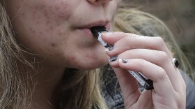 FILE - In this April 11, 2018 file photo, a high school student uses a vaping device near a school campus in Cambridge, Mass.