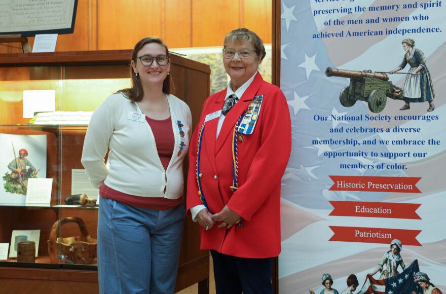 Brianna O'Shea, who leads the local Daughters of the American Revolution "E Pluribus Unum Educational Initiative," left, and Phyllis Breen, regent of the Irondequoit Chapter of the Daughters of the American Revolution, stand beside an exhibit exploring Rochester's connections to the American Revolution and its legacy. The exhibit features original artifacts from the New York State Museum and local collections and is presented by the Office of Rochester & Monroe County History, the Irondequoit Chapter of the Daughters of the American Revolution, and the Sons of the American Revolution.