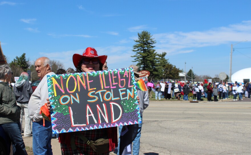 Jaclyn Lewis of Peoria holds a sign that says "None Illegal on Stolen Land." The sign is pink, blue red and green. 