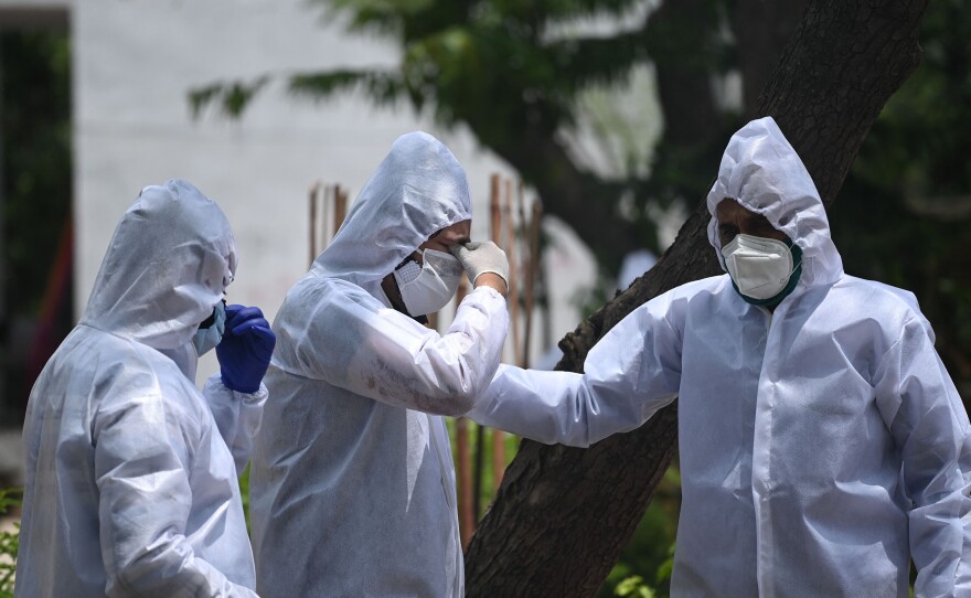 At a cremation ground in New Delhi on Tuesday, relatives wearing personal protective equipment mourn during the cremation of a family member who died after contracting COVID-19.