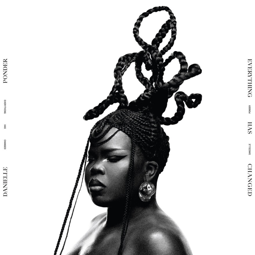 A black and white photo of a woman with her hair braided into a display of loops above her head.