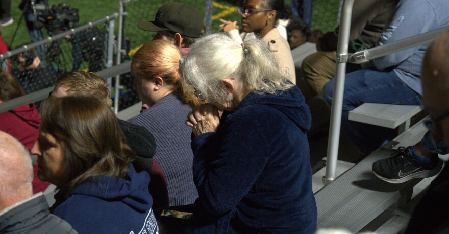 A woman in the crowd bowing her head in prayer.