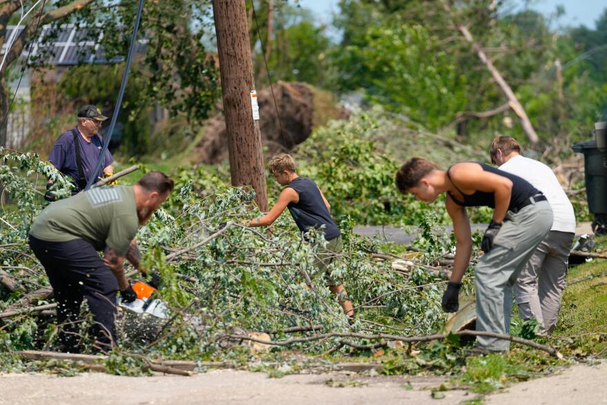 Volunteers help clear tree limbs near a damaged house after a tornado hit the day before in Appleton, Wis., Tuesday, July 28, 2026. (AP Photo/Kayla Wolf)