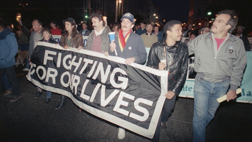 Marchers at a candlelight vigil in San Francisco, Calif., carry a banner to call attention to the continuing battle against AIDS on May 29, 1989. The city was home to the nation's first AIDS special care unit. The unit, which opened in 1983, is the subject the documentary <em>5B.</em>