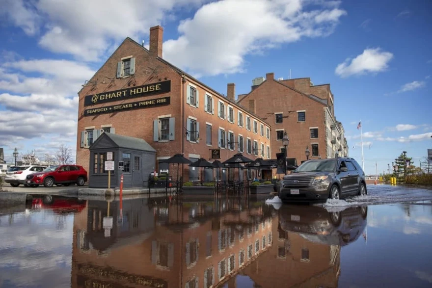 A car drives through flood water by the Chart House on Boston's Long Wharf during a November king tide.