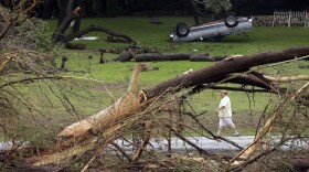 A man walks along a section of the Blanco River on Tuesday where sweeping floodwaters overturned vehicles and knocked down trees in Wimberley, Texas.