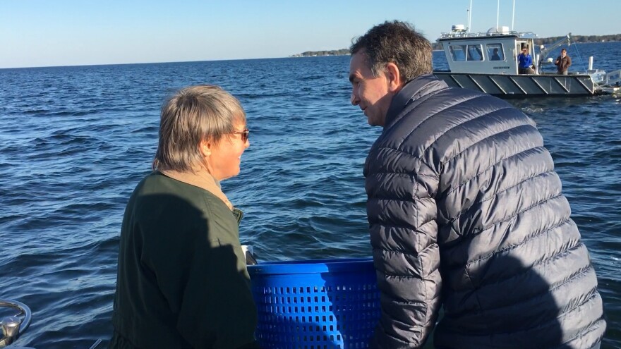 Secretary of Natural and Historic Resources Ann Jennings and Gov. Northam dump rocks they and others signed onto a newly completed oyster sanctuary in the Piankatank River.