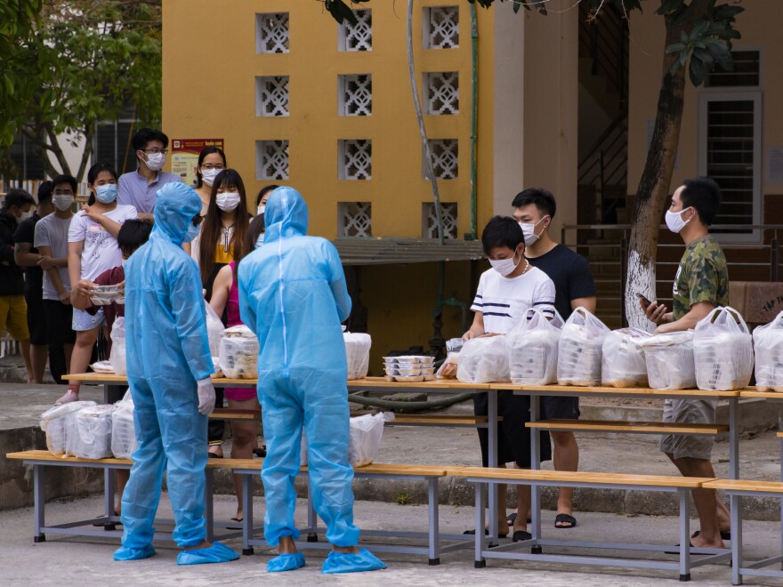 Residents at the quarantine center line up to get dinner.