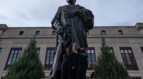Demonstrators stand on the base of a Christopher Columbus statue in front of City Hall during a protest against police brutality Saturday in downtown Columbus, Ohio.