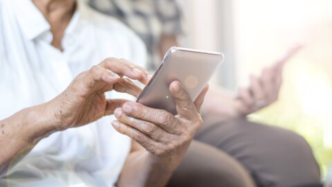 This stock photo shows a senior citizen using a smartphone.
