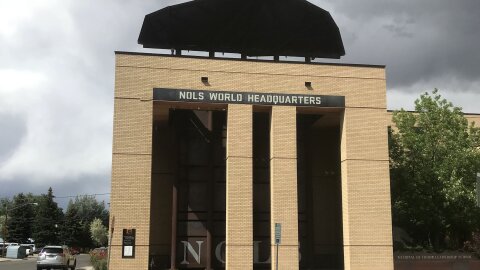 A tall brick building with "NOLS World Headquarters" above the entrance.