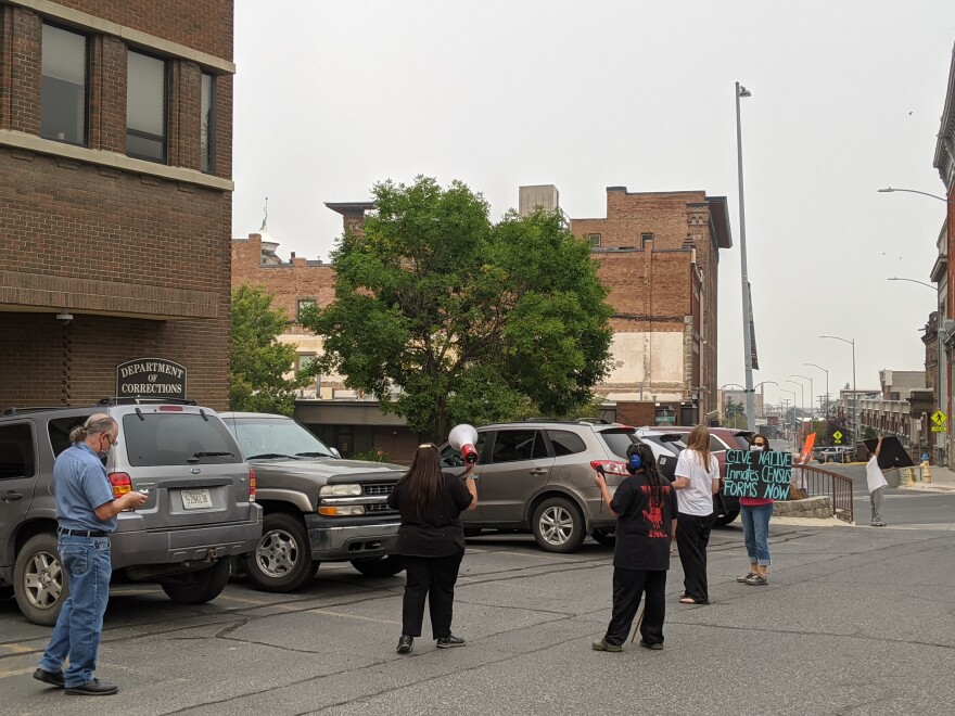 Six people wave signs and a megaphone in a parking lot.