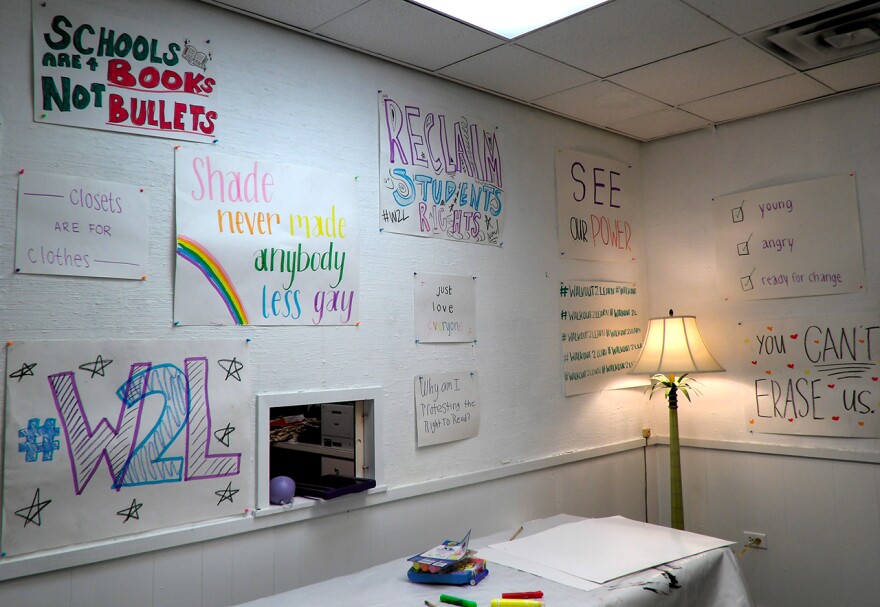 A white wall with various posters with messages