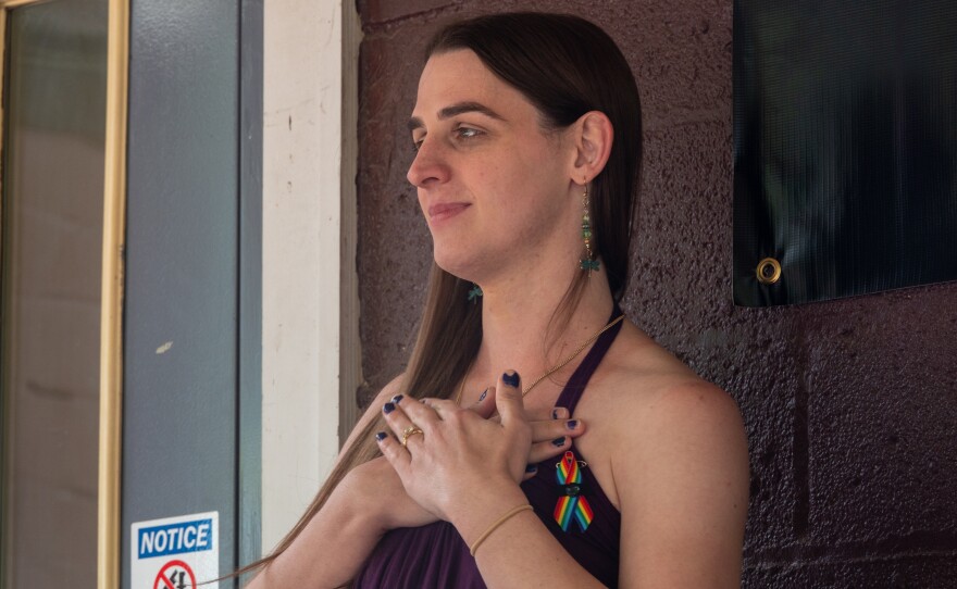  woman stands with hands clasped over her heart