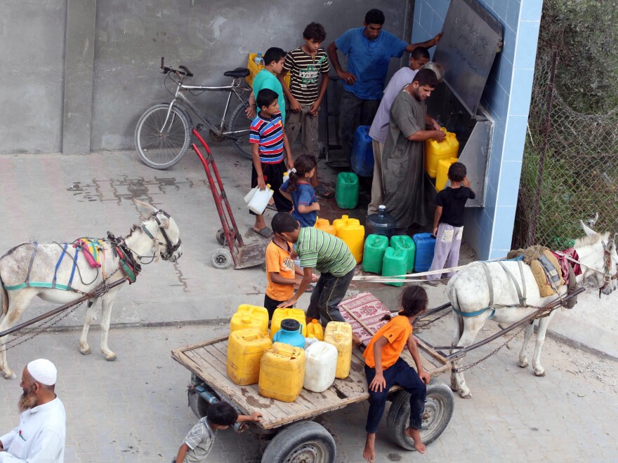 Palestinians fill their bottles with potable water at a water purification station in Deir al-Balah, central Gaza Strip, in July. About 95 percent of the municipal water is undrinkable, and only about 40 percent of homes have access to potable water on a regular basis.